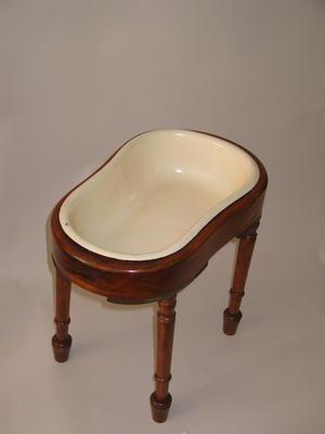 Enamel chamber pot with wooden surround and four detachable legs, packed in wooden crate, fastened with two leather straps.