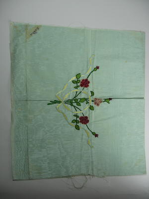 Rectangular piece of green silk decorated with embroidered red roses and yellow ribbon. The words 'To Dorris' are written in one corner.