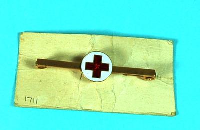 Gold brooch pin with red cross on white background