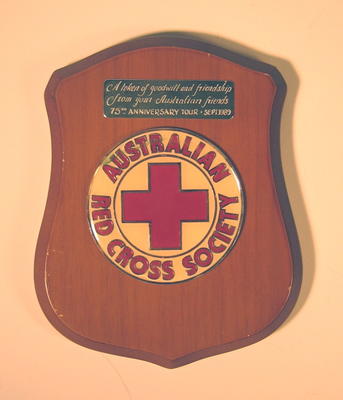 Small wooden shield gifted to the British Red Cross by the Australian Red Cross Society to commemorate the 75th Anniversary Tour in September 1989