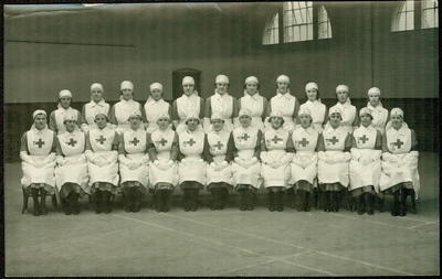 photograph of a group of female VADs in indoor uniform, seated inside a hall