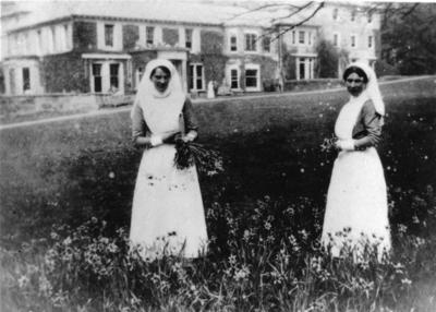 Two nurses holding flowers in the grounds of Thorncombe Military Hospital in Bramley, Surrey