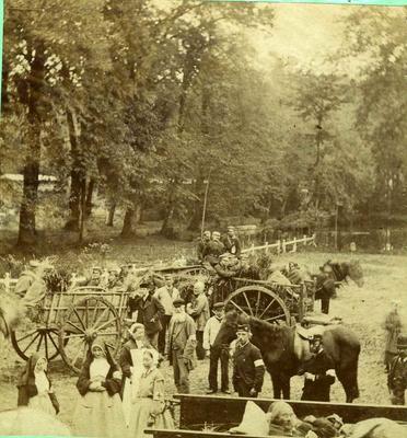Nurses and [orderlies] with horse drawn ambulances bearing patients