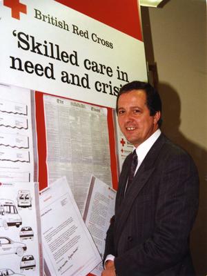 Mike Whitlam standing next to the British Red Cross visual identity handbook exhibition