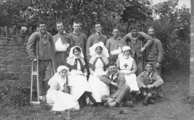 Two Queen Alexandra's nurses and two VAD members in nursing uniform with group of patients in hospital blue at Southmead Hospital, Bristol