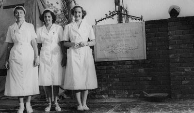 Three female Red Cross personnel [wearing white tropical uniforms] standing next to the foundation stone for the new Sudan Red Cross Headquarters