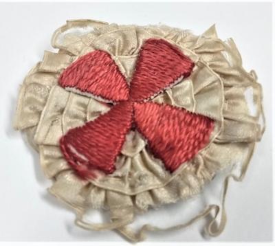 Embroidered red cross in the shape of a rosette