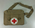 manilla coloured canvas bag with front flap fastening and featuring red cross in white circle to front centre