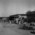 Black and white photograph. Groups of refugees outside huts at Multan Cantonment Camp in Pakistan