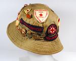 Khaki sunhat ('camp hat') with many Red Cross badges. Formerly belonged to Jean Davis, youth worker, of Maldon Centre.