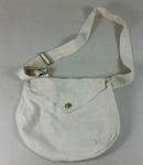 cream coloured canvas bag with front flap fastened by a red cross button