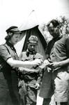 Woman in British Red Cross uniform, with man and boy looking at a message form