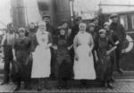Two Red Cross nurses posing with a group of male and female fisher folk