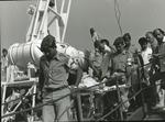 Male Red Cross personnel carrying wounded on a stretcher with a drip down the gangplank from a ship