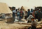 Kurdish children around women cooking in a refugee camp