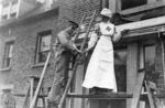 Photograph of a British Red Cross nurse and wounded soldier painting the outside of a hospital