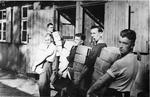 Prisoners of War from Stalag XXA carrying Red Cross food parcels into camp huts