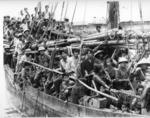 Black and white photograph. A large group of Vietnamese boat people crowded onto a wooden boat in Hong Kong