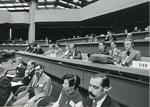 A group of people sitting at benches wearing headphones at a Diplomatic Conference in Geneva