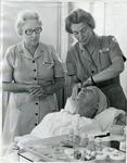 Two female British Red Cross beauticians giving a beauty treatment to an elderly woman in Buckinghamshire