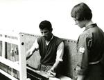 Black and white photograph. Therapy for a seriously disabled patient in Morocco, man being taught weaving by a Red Cross occupational therapist.