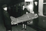 Black and white photograph of a patient on the special stretcher being transferred to a train by British Red Cross members
