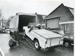 Black and white photograph of a Red Cross jeep being loaded into a lorry for transportation